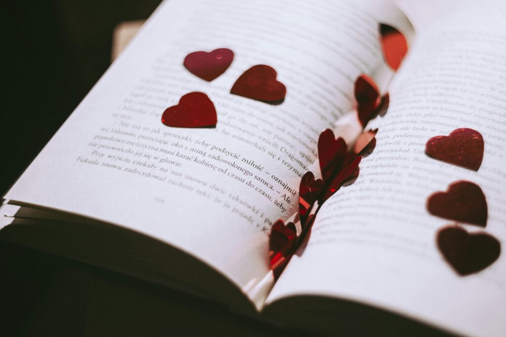 An open book adorned with red heart-shaped confetti, perfect for Valentine's or romantic themes.